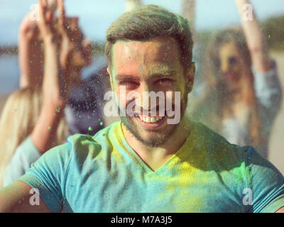 Selfie portrait von einem muskulösen Mann Feiern von Holi Festival mit seinen Freunden. Sein Gesicht und seine Kleider sind mit farbigen Pulver bedeckt. Stockfoto