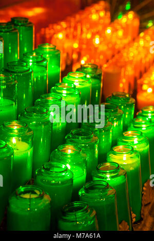 Grünen und roten Kerzen an einem Votive Rack in einer katholischen Kirche. Stockfoto