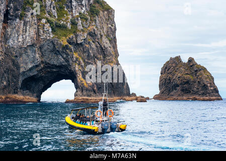 Touristische Boot nähert sich das Loch im Felsen auf Piercy (Motukokako) Insel, die nur aus Cape Brett in der Bucht von Inseln, North Island, Neuseeland Stockfoto