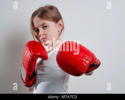 Kleines Mädchen in Boxhandschuhen auf weißem Hintergrund Stockfoto