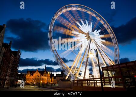 Drehende Riesenrad in der Altstadt von Danzig, Polen in der Nacht. Green Gate im Hintergrund Stockfoto