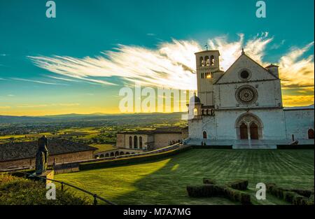 Vorderansicht der Basilika des Heiligen Franziskus von Assisi. Sunshine Spikes von hinter der Basilika, Färbung die gelbe Wolke 12 August 2016 19:35 Stockfoto