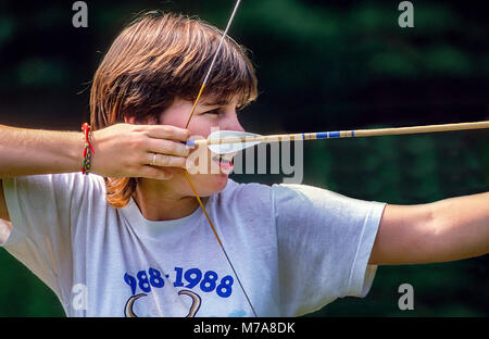 Ein junges Mädchen im Summer Camp konzentriert sich auf ihr Ziel beim Bogenschießen üben im Summer Camp in Vermont, USA, Nordamerika. Stockfoto