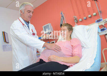 Männlicher Arzt Prüfung der schwangeren Frau im Krankenhaus Stockfoto