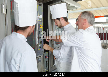 Junge Bäcker die ungebackene Brot im heißen Backofen in Bäckerei Stockfoto