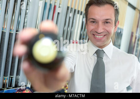 Junge gut aussehender Geschäftsmann holding Billard Kugel Stockfoto