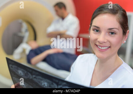 Weibliche Radiologen mit Kollegen stehen, die von MRT-Gerät Stockfoto