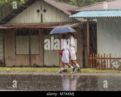 Ambon, Indonesien - 12. Februar 2018: Kinder in der weißen Uniformen zurück aus der Schule in der Regen Stockfoto