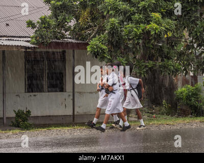 Ambon, Indonesien - 12. Februar 2018: Kinder in der weißen Uniformen zurück aus der Schule in der Regen Stockfoto