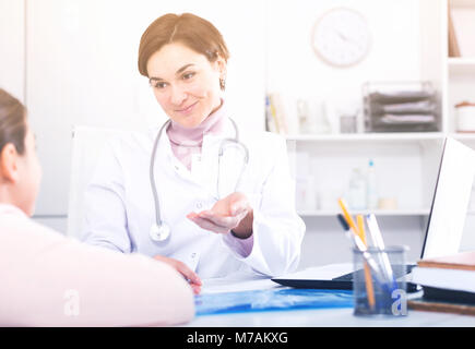 Arzt füllt die Karte des Patienten für Mädchen und fragt sie über Gesundheit in der Arztpraxis Stockfoto