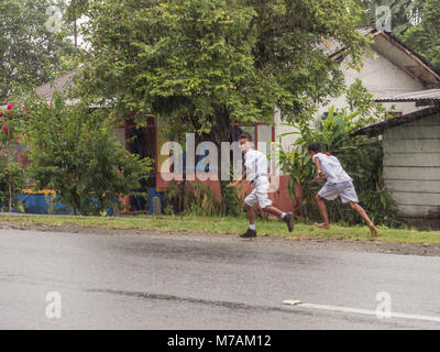 Ambon, Indonesien - 12. Februar 2018: Kinder in der weißen Uniformen zurück aus der Schule in der Regen Stockfoto