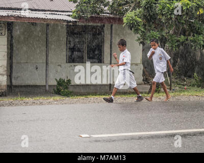 Ambon, Indonesien - 12. Februar 2018: Kinder in der weißen Uniformen zurück aus der Schule in der Regen Stockfoto