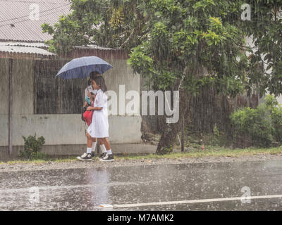 Ambon, Indonesien - 12. Februar 2018: Kinder in der weißen Uniformen zurück aus der Schule in der Regen Stockfoto