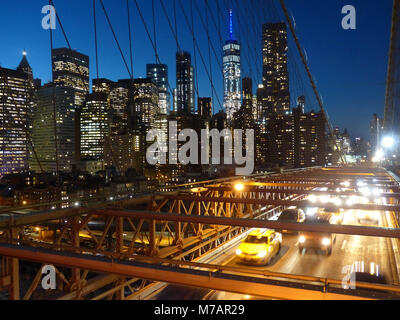 New York Brooklyn Bridge, 1883 erbaut, mit Fahrzeug Verkehr während der Dämmerung und Downtown Manhattan office Towers Stockfoto