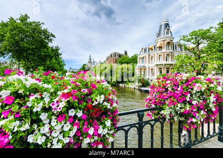 Kanal in Amsterdam, Niederlande, mit Blumen auf einer Brücke Stockfoto