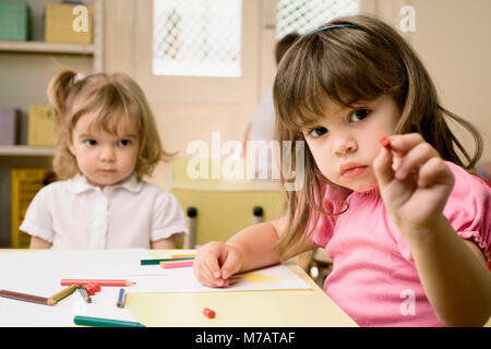 Portrait eines Mädchens mit einem Farbstift mit ihrem Freund im Hintergrund sitzen Stockfoto