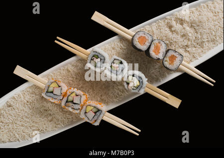 Nahaufnahme der verschiedenen Sushi mit Stäbchen auf dem Teller Stockfoto