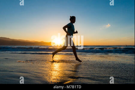 Frau Jogging am Strand bei Sonnenuntergang. Stockfoto