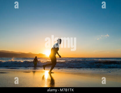 Frau Jogging am Strand bei Sonnenuntergang. Stockfoto