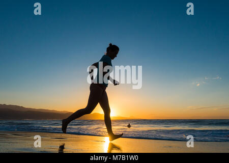 Frau Jogging am Strand bei Sonnenuntergang. Stockfoto