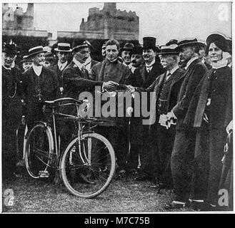 Foto eines Postboten, der König Georg V. einen Brief mit dem Fahrrad überbringt, der die Postdienste und die königliche Interaktion im Großbritannien des frühen 20. Jahrhunderts veranschaulicht. Stockfoto