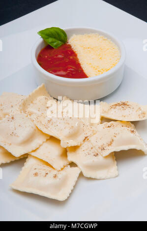 Nahaufnahme von Ravioli mit Tomatensauce und geriebenem Käse serviert Stockfoto