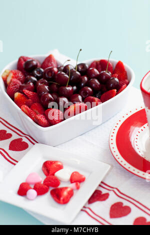 Vogelperspektive Blick auf eine herzförmige Schüssel gefüllt mit verschiedenen Beeren Stockfoto