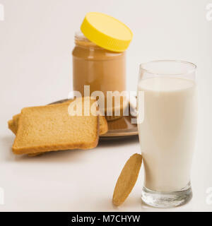 Erdnussbutter-Glas mit einem Glas Milch und Brot Scheiben Stockfoto