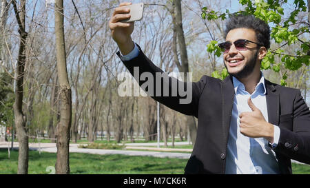 Man ruft Schwester per Telefon und zeigen Daumen hoch, Frieden Hand singen Stockfoto