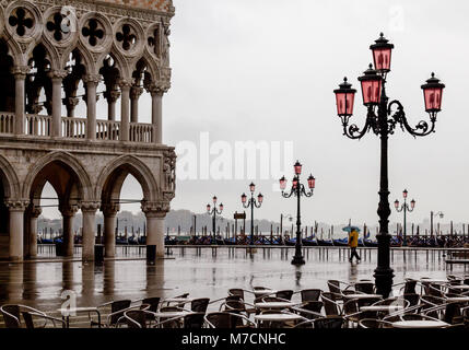 Einsamer Mann, der einen Regenschirm Spaziergänge entlang der Riva degli Schiavoni, Venedig, im Regen. Der Dogenpalast Venedig und die Straßenlaternen sind sichtbar. Stockfoto