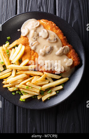 Knusprig gebratene Schweinekoteletts (Jaeger Schnitzel) mit Sauce und Pommes frites Close-up auf einem Teller. Vertikal oben Ansicht von oben Stockfoto