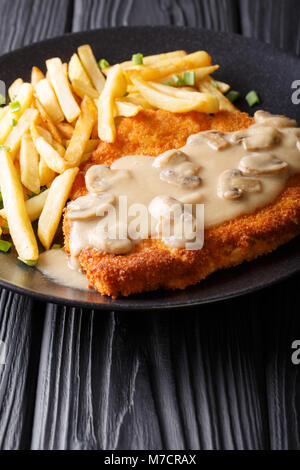 Köstliche Jaeger Wiener Schnitzel mit Sauce und Pommes frites Close-up auf einem Teller. Vertikale Stockfoto