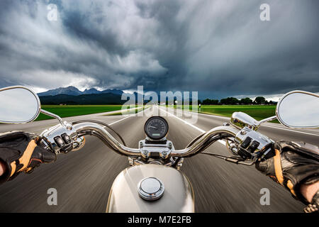 Biker auf einem Motorrad die Straße hinunter in ein Gewitter - Forggensee und Schwangau, Deutschland Bayern rast Stockfoto