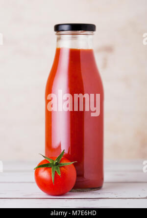 Glas Flasche Tomatenmark mit rohen frische organische Tomaten auf Holzuntergrund Stockfoto