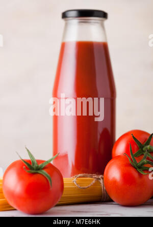 Glas Flasche Tomatenmark mit rohen Spaghetti und frische Bio Tomaten auf Holzuntergrund Stockfoto