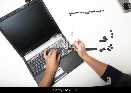 Techniker heben die Beschriftung der Tasten auf der Tastatur eines offenen Laptop Computer in einem Reparatur- oder Wartungsarbeiten Konzept Stockfoto