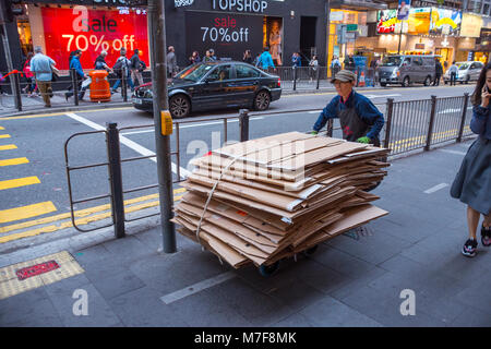 Mann Schieben von Kartons für Recycling stack, Hong Kong Stockfoto