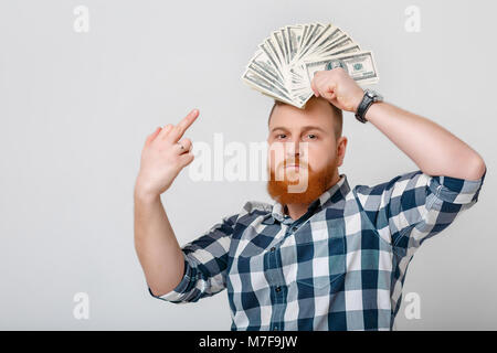 Mann mit dem roten Bart in Plaid Shirt Holding eine Menge 100-Dollar-Scheine. Geld Stockfoto