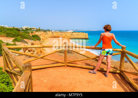 Junge Frau touristische stehend auf Sicht Plattform und Suchen am Strand in Armacao de Pera, Algarve, Portugal Stockfoto