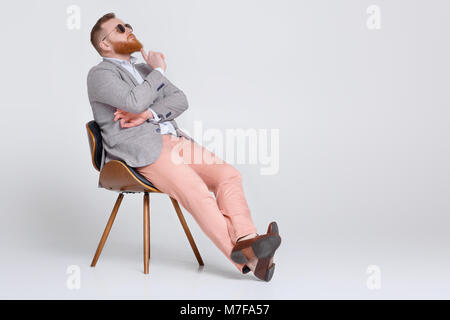 Rothaarige Bart Mann in lässiger Anzug und Sonnenbrille auf grauem Hintergrund. Stockfoto