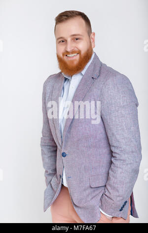 Lächelnd rothaarige Bart Mann in lässiger Anzug auf grauem Hintergrund. Stockfoto