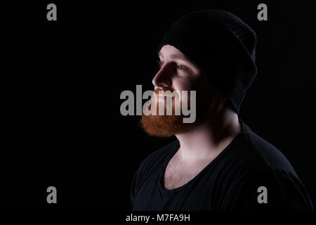 Profil von Red bärtigen Mann in hat auf schwarzem Hintergrund Stockfoto