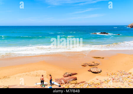 PRAIA DO AMADO STRAND, PORTUGAL - 15. MAI 2015: Surfer am Praia do Amado Strand mit Wellen schlagen. Algarve Region ist beliebt Holi Stockfoto