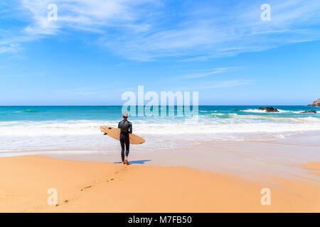 PRAIA DO AMADO STRAND, PORTUGAL - 15. MAI 2015: Surfer gehen auf Praia do Amado Strand mit Wellen schlagen. Algarve Region ist beliebt Holida Stockfoto