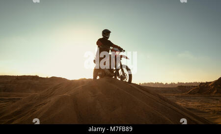 Professionelle Reiter auf FMX Motocross Motorrad steht auf der Düne und mit Blick auf ganze Extreme Off-Road Gelände, dass er Reiten Heute. Stockfoto