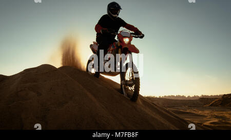 Professionelle Reiter auf FMX Motocross Motorrad steht auf der Düne und mit Blick auf den Off-Road-Track, fährt dann nach unten. Stockfoto