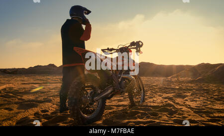 Low Angle Shot der professionellen Motocross Fahrer auf seinem Helm und Vorbereitung für das Reiten auf seinem Dirt Bike. Stockfoto