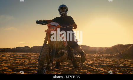 Vorderansicht des professionellen Motocross Fahrer Sättel seine FMX Dirt Bike auf dem Sand/Dirt Track. Stockfoto