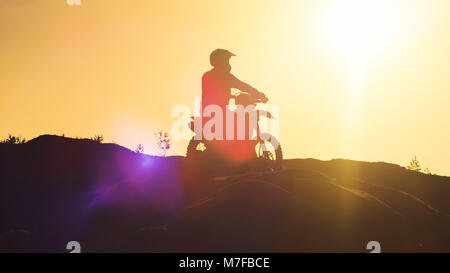 Professionelle Reiter auf FMX Motocross Motorrad steht auf einer Düne mit Blick auf Extreme Off-Road Gelände, dass er Reiten Heute. Stockfoto