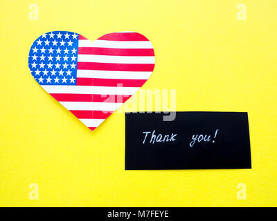 Vielen Dank, dass Sie sich auf einer Schiefertafel mit der amerikanischen Flagge auf gelben Hintergrund Zeichen, USA Stockfoto